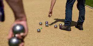 Boulespiel auf dem Campingplatz: Metallkugeln liegen auf dem Boden, ein Spieler steht daneben.