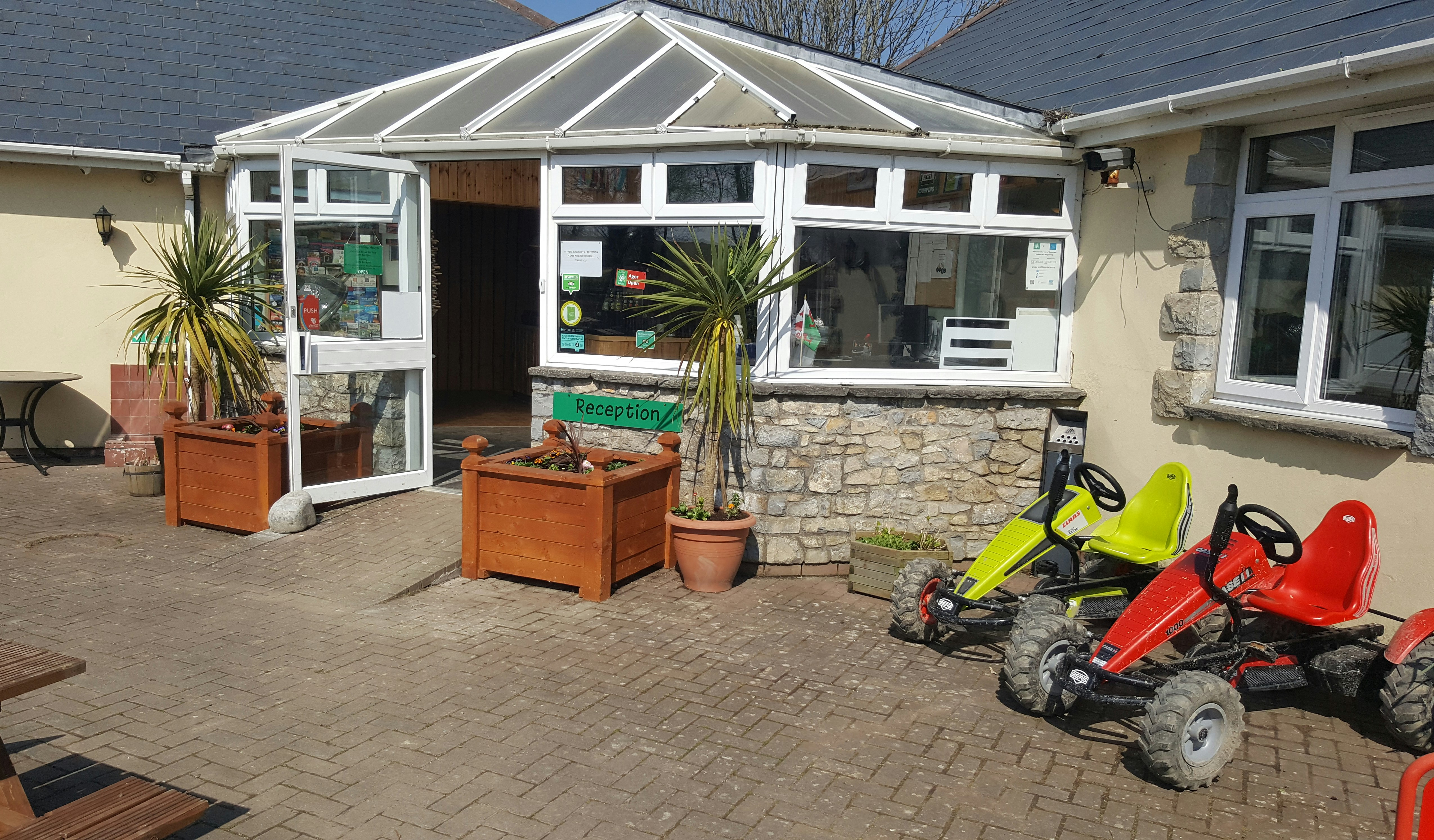 Acorn Camping and Caravan Site - Eingang zum Gebäude der Rezeption mit zwei davor stehenden Kettcars