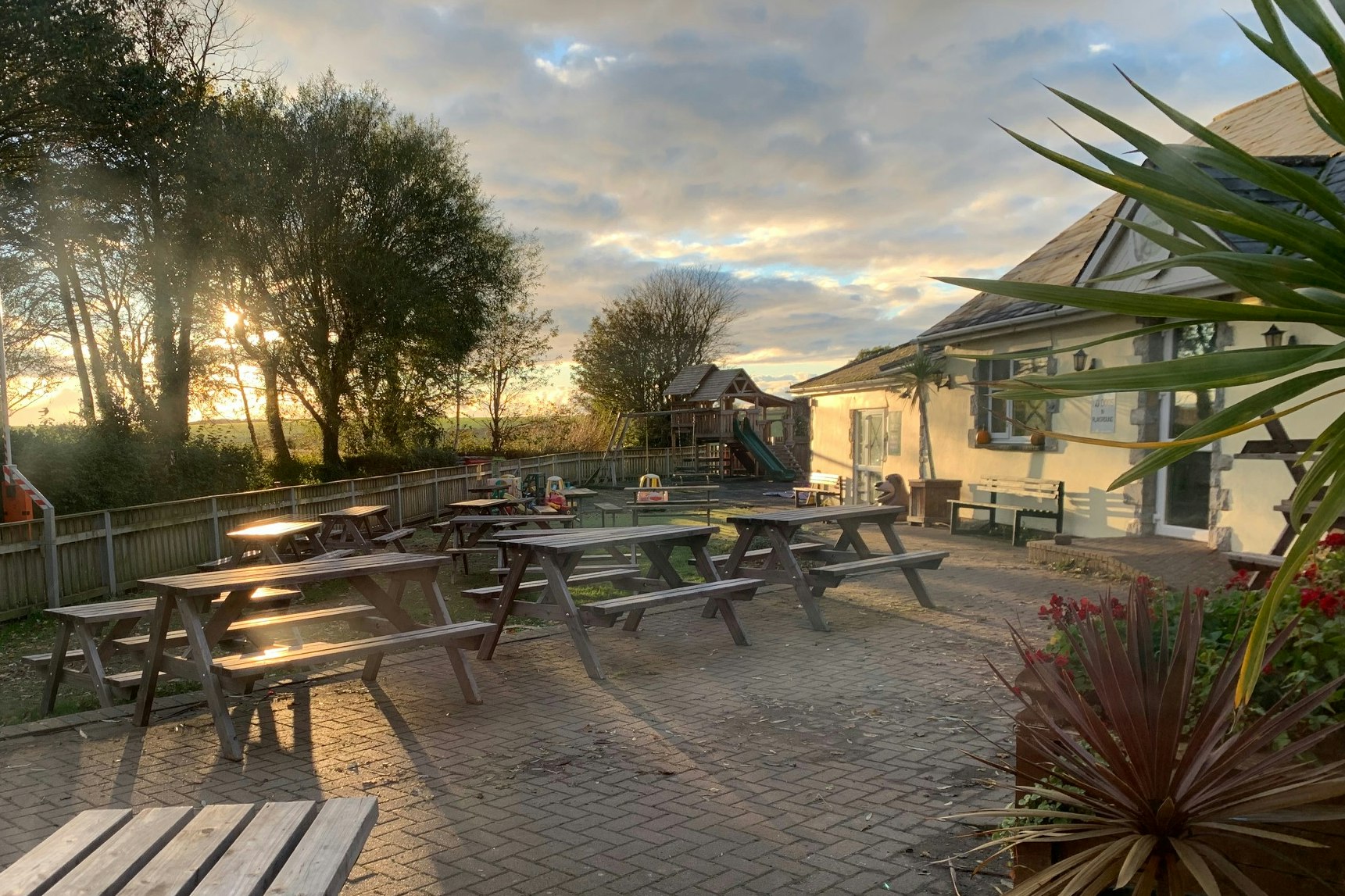 Acorn Camping and Caravan Site - Picknickstelle mit Bänken und Tischen mit Blick auf den Spielplatz in der Abendsonne
