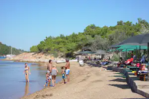 Ada Camping - Strand vom Campingplatz mit Sonnenschirmen und Liegestühlen am Mittelmeer