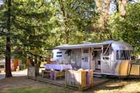 Albirondack Parc - Wohnmobil mit Holzterrasse und Außentisch im Schatten der Bäume