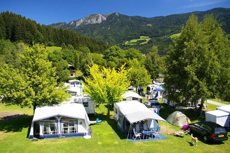 Alpencamp Kärnten - Luftaufnahme auf den Wohnwagen- und Zeltstellplatz zwischen Bäumen mit den Alpen im Hintergrund