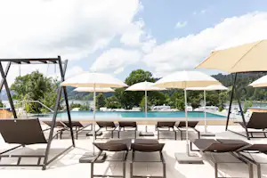 Alpsee Camping - Campingplatz mit Pool Liegestühlen und Sonnenschirmen