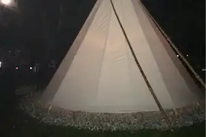 Zelt bei Nacht auf einem Campingplatz, mit Abspannseilen und Zeltplane auf dem Boden.