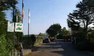 Schilder am Camping-Eingang mit Hinweis „Anchor Caravan Park“, dahinter eine Zufahrtsstraße und Bäume.