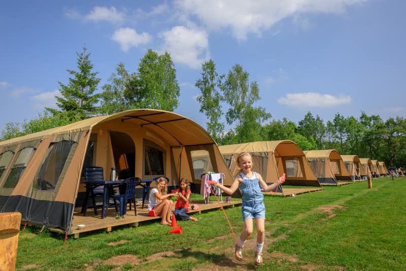 Ardoer Camping De Reeënwissel - Kind spielt vor dem Safari Zelt auf dem Zeltplatz vom Campingplatz