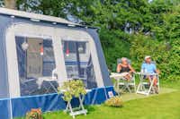 Ardoer Camping Ginsterveld -  Camper sitzen vor dem Wohnmobil auf der Sonne