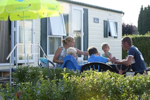 Ardoer Camping International - Camper Familie am Esstisch auf der Veranda vom Mobilheim auf dem Campingplatz