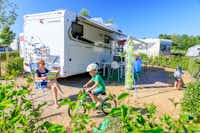 Ardoer Camping Julianahoeve - Camper sitzen vor dem Wohnmobil auf der Sonne und Kinder spielen