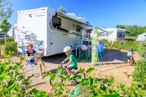 Ardoer Camping Julianahoeve - Camper sitzen vor dem Wohnmobil auf der Sonne und Kinder spielen