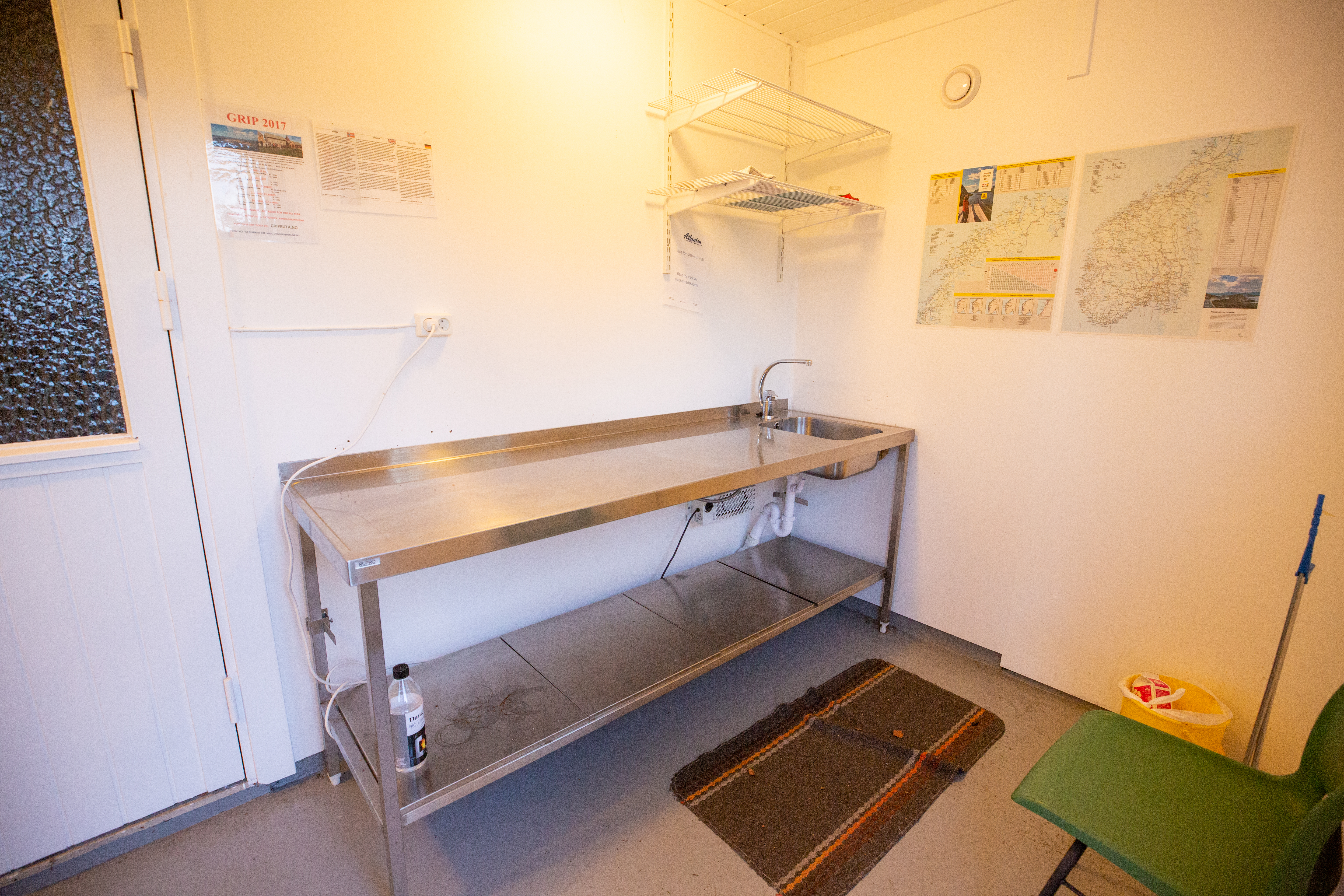 Etagenbett in einem kleinen Campingzimmer mit zwei Matratzen, Teppichboden und Wandkarten an der hellen Wand.