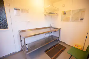 Etagenbett in einem kleinen Campingzimmer mit zwei Matratzen, Teppichboden und Wandkarten an der hellen Wand.