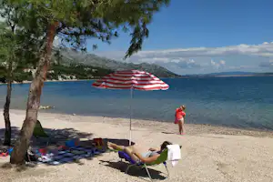 Auto Camp Navis - Gäste am Strand im Schatten der Bäume