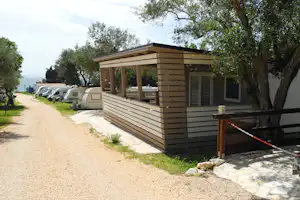 Autocamp Nordsee - Mobilheim mit überdachter Veranda mit weiteren Wohnwagen im Hintergrund