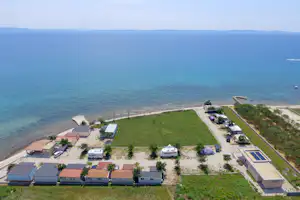 Campingplatz direkt am Meer, Wohnwagen und Autos auf Stellplätzen, Blick auf das blaue Wasser und die Küste.