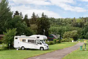 Autokamp Sedmihorky - Standplätze mit einem Wohnmobil und umringt von Wald mit Blick auf Gebäude