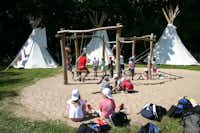 Autokamp Sedmihorky - Kinderspielplatz mit Klettergerüst und spielenden Kindern, dahinter drei weiße Tipi-Zelte
