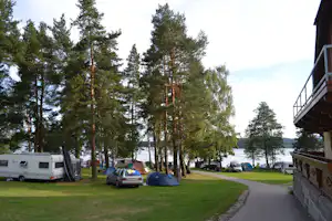 Autokemp Karlovy Dvory II - Wohnwagen- und Zeltstellplatz vom Campingplatz zwischen Bäumen mit Blick auf See
