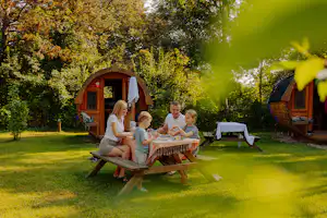 AZUR Campingpark Regensburg - Familie sitzt an einem Picknicktisch vor den Schlaffässern