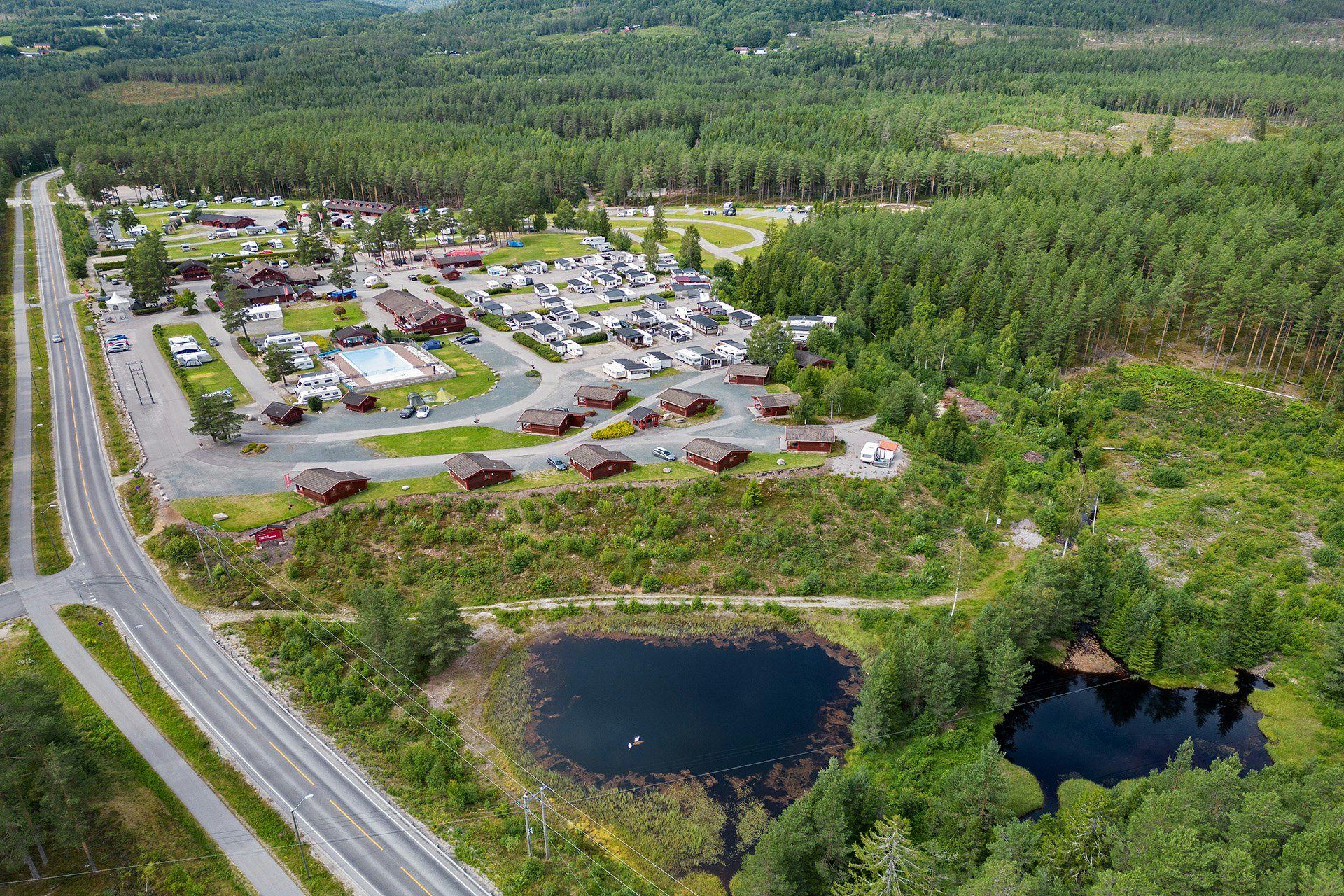 First Camp Bø - Telemark  Bø Camping  - Blick auf den Campingplatz aus der Vogelperspektive mit Wald und Seen in der Umgebung