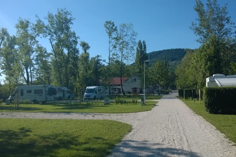 Badacsony Camping - Blick auf die Wege und Standplätze mit Wohnmobilen, im Hintergrund ein Gebäude und grüne Hügel