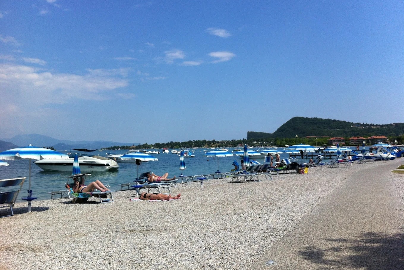 Baia Holiday Romantica a Lago - Liegestühle und Sonnenschirme am Badestrand