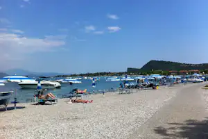 Baia Holiday Romantica a Lago - Liegestühle und Sonnenschirme am Badestrand
