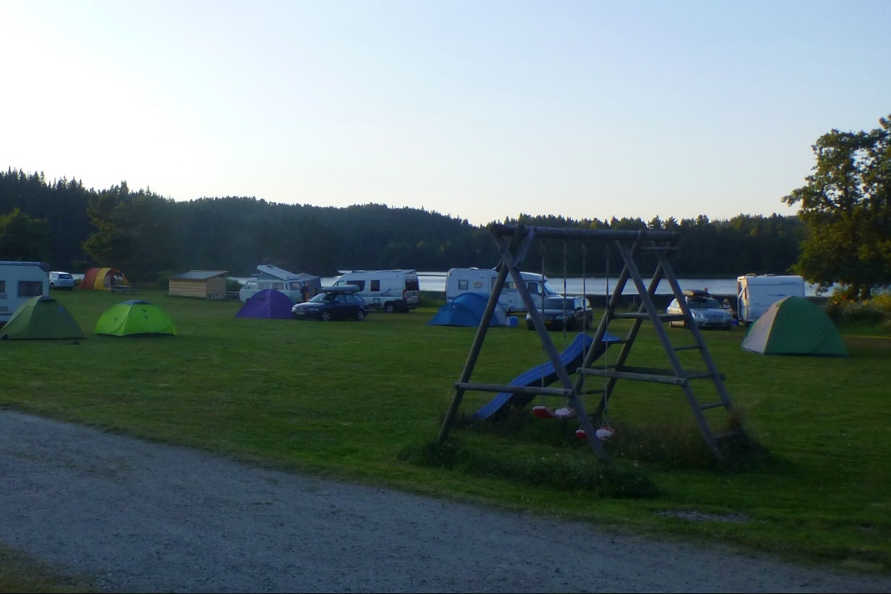 Bjønndalen Camp - Stellpaltzwiese mit einer Rutsche und einer Schaukel für Kinder im Vordergrund