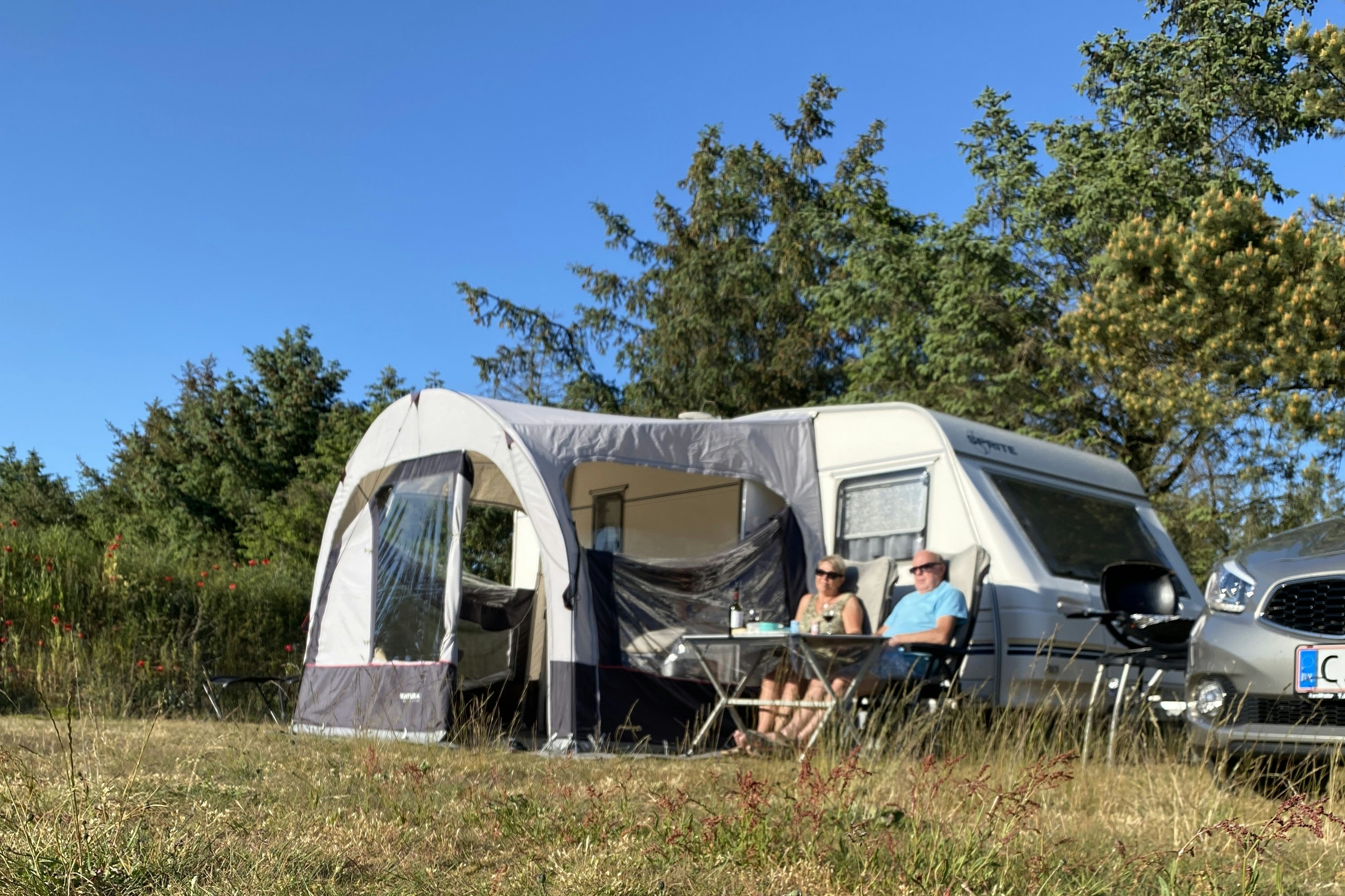 Blokhus Natur Camping - Ehepaar sitzt auf ihrem Standplatz und genießt die Sonne