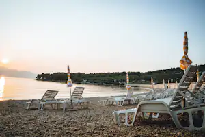 Boutique Camping Bunja - Badestrand mit Liegestühlen und Sonnenschirmen