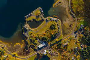 Luftaufnahme eines Campingplatzes am See mit Wegen, Stellplätzen und mehreren Gebäuden am Ufer.