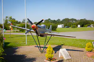Großes Modellflugzeug am Wegesrand auf dem begrünten Campingplatz Cakes and Ale Park