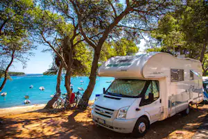 Camp Arena Runke - Schattiger Wohnwagenstellplatz mit Blick auf Wasser auf dem Campingplatz