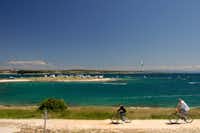 Camp Arena Stupice - Radler auf einem Weg am adriatischen Meer mit dem Campingplatz im Hintergrund