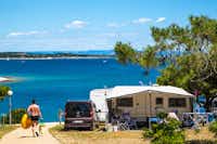 Camp Arena Stupice - Wohnwagen mit Vorzelt auf einem Stellplatz und einem Camper auf dem Weg zum Strand
