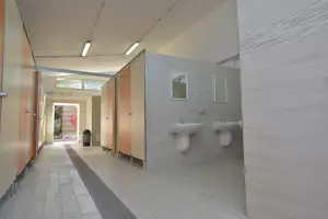 Campeggio Villaggio Torre del Porticciolo - Innenansicht eines Sanitärgebäudes mit Toiletten- und Duschkabinen und Waschbecken