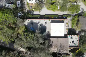 Luftaufnahme eines Campingplatzes mit Wohnwagen, Wegen und mehreren Stellplätzen zwischen Bäumen und Grünflächen.