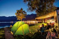 Camping Aaregg - Camper sitzen abends vor ihrem Wohnwagen und schauen auf den Brienzersee