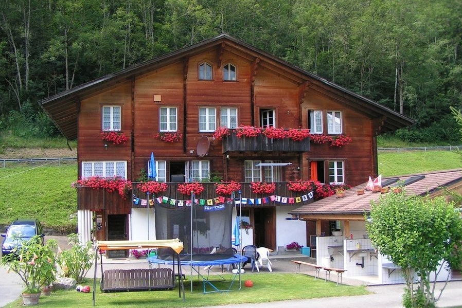 Camping Aareschlucht - Hauptgebäude des Campingplatzes mit Trampolin und Hollywoodschaukel davor