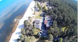 Campingplatz am Fluss mit Wald, Luftaufnahme: Gebäude, Wege und Stellplätze entlang des Ufers.