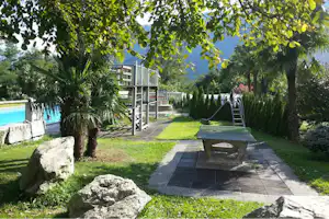 Camping Al Censo - Spielplatz mit kleiner Rutsche und Tischtennisplatte mit Swimmingpool im Hintergrund