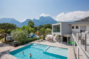 Camping Al Porto - Das Hauptgebäude und der Swimmingpool des Campingplatzes mit Stellplätzen dahinter