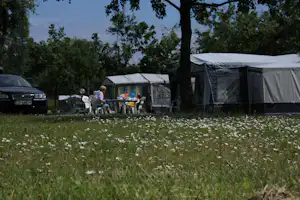 Camping Alexa - Gäste vor ihrem Wohnmobil auf der Wiese im Schatten der Bäume