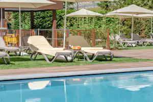 Camping Alleghe - Liegestühle unter Sonnenschirmen am Swimmingpool des Campingplatzes