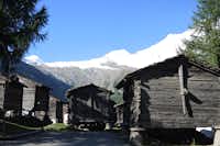 Camping am Kapellenweg - Holzhütten auf dem Campingplatz mit den Alpen im Hintergrund
