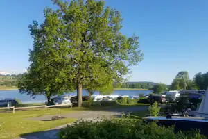 Camping am Perlsee - Wohnmobil un Wohnwagen Stellplaetze auf der Wiese mit Wasserblick