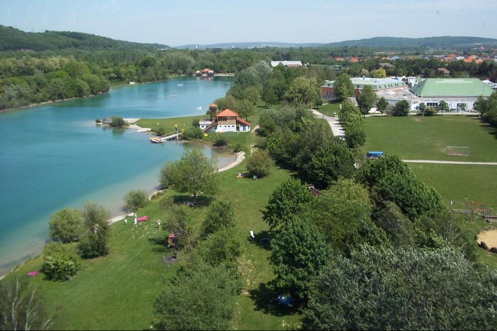 Camping am See - Luftaufnahme auf den See, an dem Der Campingplatz liegt und den Campingplatz im Hintergrund