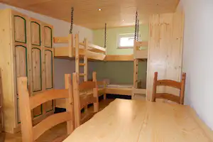 Camping Am Treidlerweg - Schlafraum mit Hochbetten und Schränken sowie Tisch und Stühlen auf dem Campingplatz