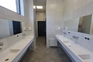 Camping-Badezimmer mit zwei langen Waschtischen, Spiegeln, Wasserhähnen und Toiletten im Flur.
