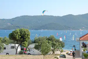 Camping Antony-Boy - Wohnwagenstellplätze mit dem Mittelmeer im Hintergrund, auf dem viele Menschen surfen